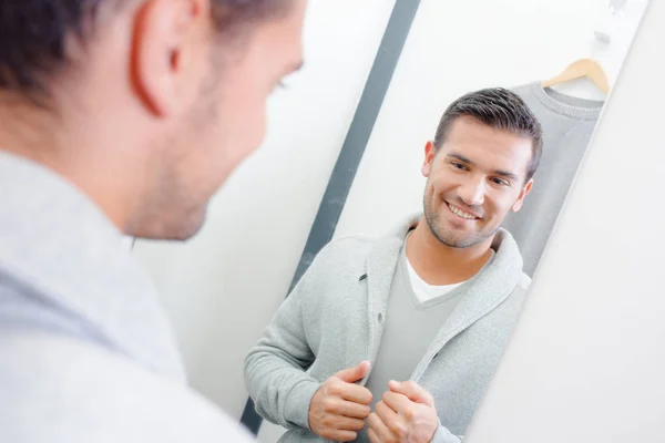 Hombre probándose la chaqueta, mirando el reflejo en el espejo —  Fotos de Stock