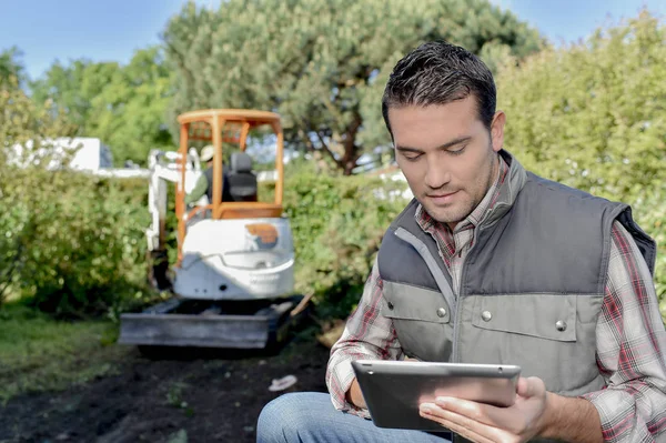 Man buiten op tablet, digger op achtergrond — Stockfoto