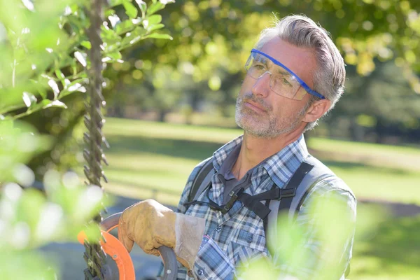 Hombre usando recortador de setos — Foto de Stock