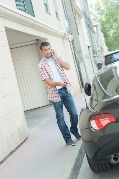 Man on telephone, unlocking car door with central locking device — Stock Photo, Image