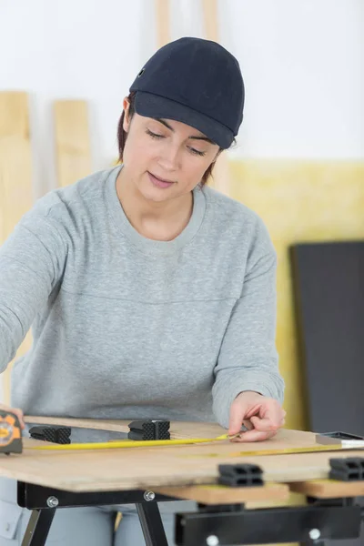 Mujer que mide una madera contrachapada —  Fotos de Stock