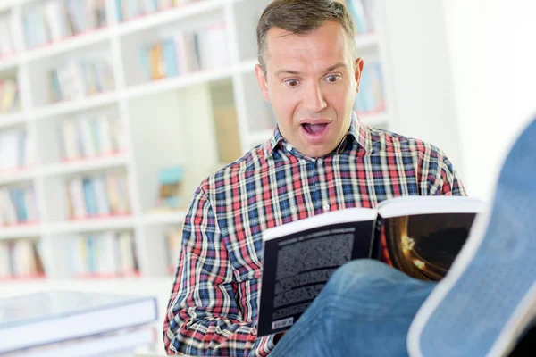 Homem leitura livro, expressão chocada — Fotografia de Stock