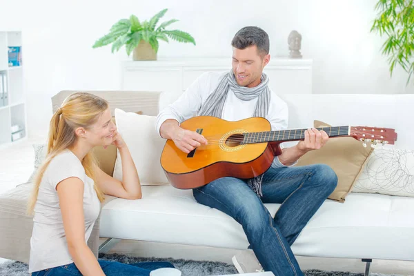 Człowiek na kanapie, gra na gitarze do Pani — Zdjęcie stockowe