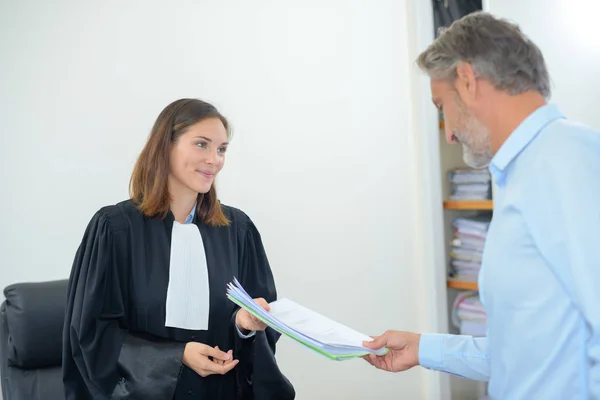 Man passing paperwork to legal worker wearing robes — Stock Photo, Image