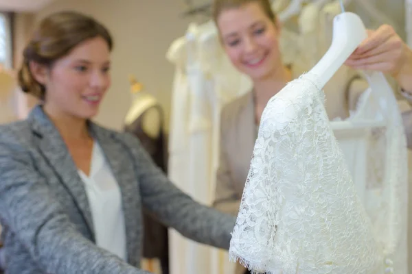 Женщина смотрит на свадебное платье в магазине — стоковое фото