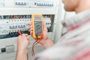 Electrician using multimeter and amperage clipart