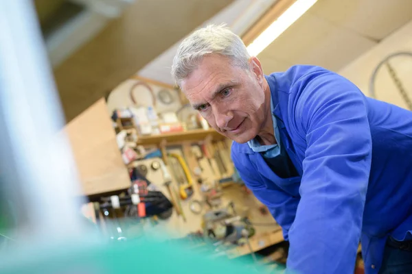 Carpintero senior que marca una medida en una tabla de madera — Foto de Stock