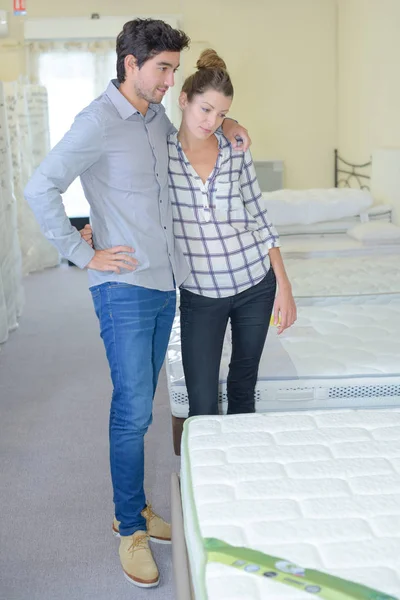 Casal escolher cama em uma loja de móveis — Fotografia de Stock