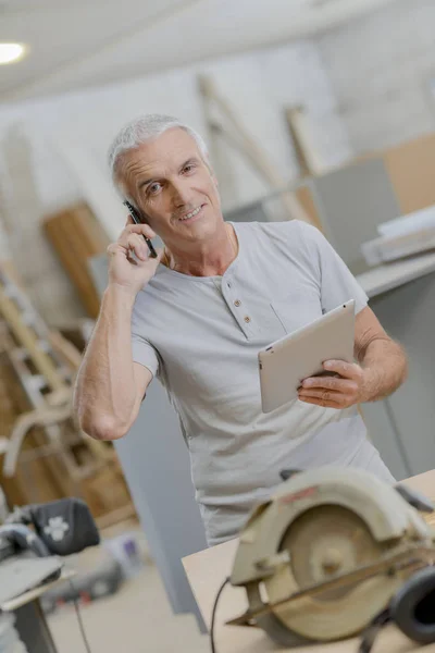 Senior carpenter embracing technology — Stock Photo, Image