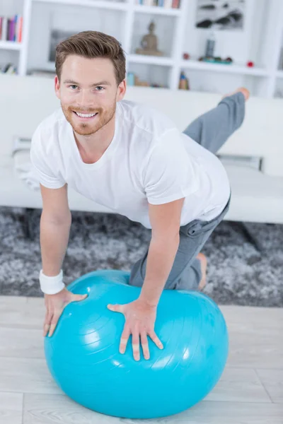 Attrayant jeune homme avec ballon suisse faire des exercices à la maison — Photo