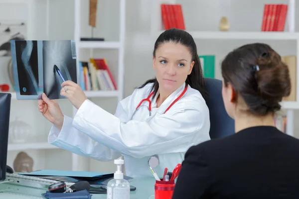 Doctora joven mostrando radiografía a paciente —  Fotos de Stock
