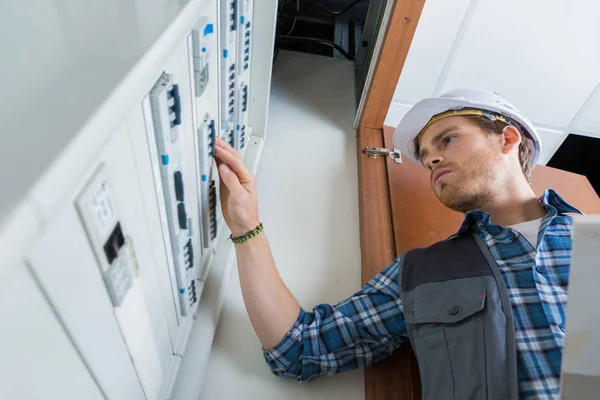 Jovem eletricista trabalhando no painel elétrico — Fotografia de Stock