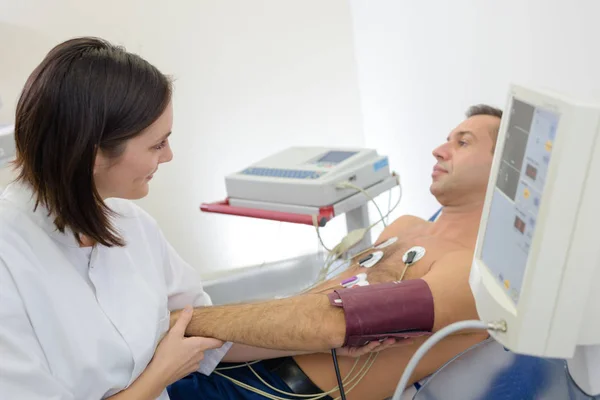 Mujer tomando presión arterial de paciente masculino —  Fotos de Stock