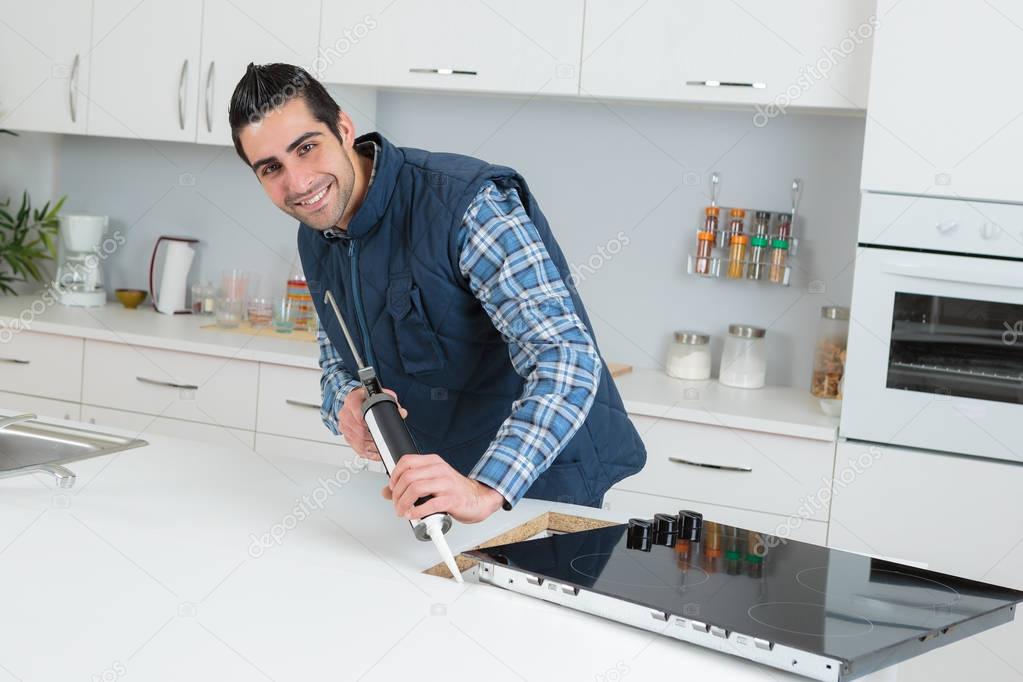 Worker installing new induction hob in modern kitchen — Stock Photo