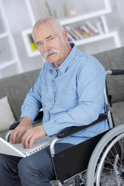 Senior i rullstol med en dator — Stockfoto