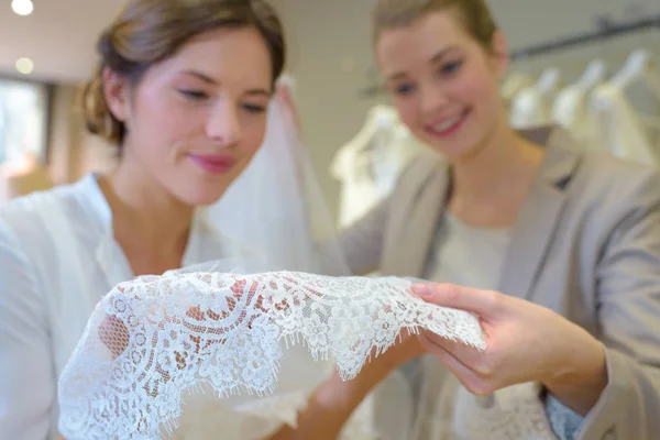 Women looking at lace of wedding dress — Stock Photo, Image