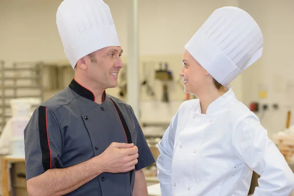 Dwóch specjalistów szefowie mówi i uśmiecha się w kuchni — Zdjęcie stockowe
