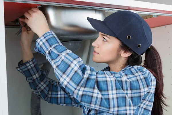 Vrouw passende wastafel en loodgieter — Stockfoto