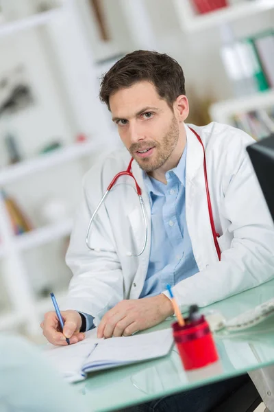 Schöner junger Arzt bei der Arbeit in seinem Büro — Stockfoto