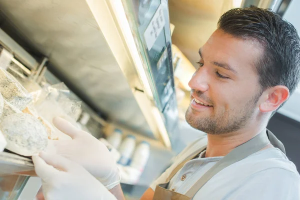 Assistente di negozio che tiene un formaggio — Foto Stock