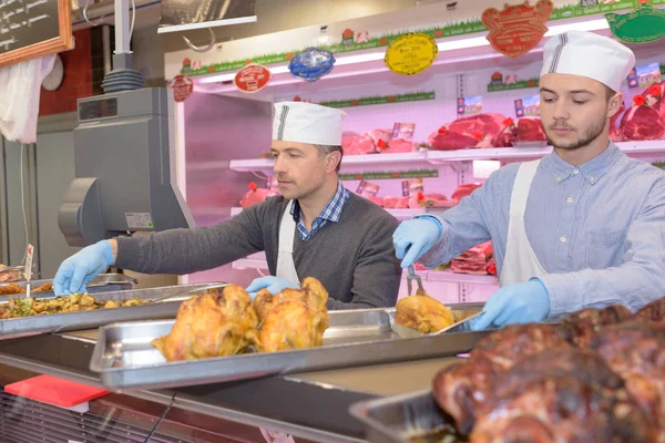 Slaktare visar kokt kyckling ovanpå counter — Stockfoto