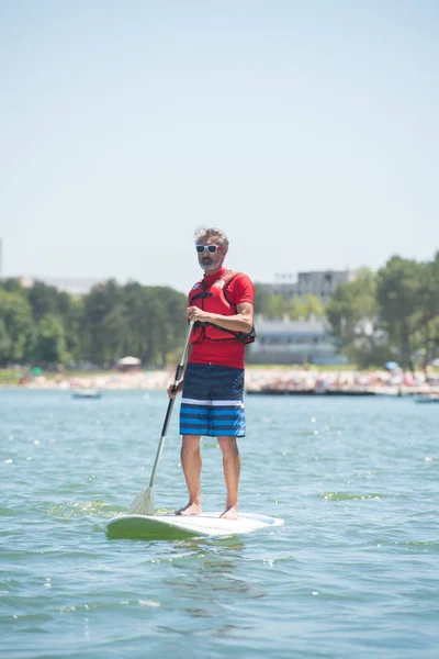Чоловік насолоджується поїздкою на озері з дошкою для весла — стокове фото
