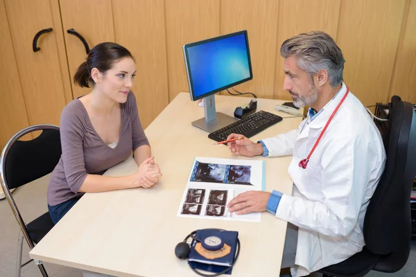 Arzt betrachtet Scan-Bilder mit Patient — Stockfoto