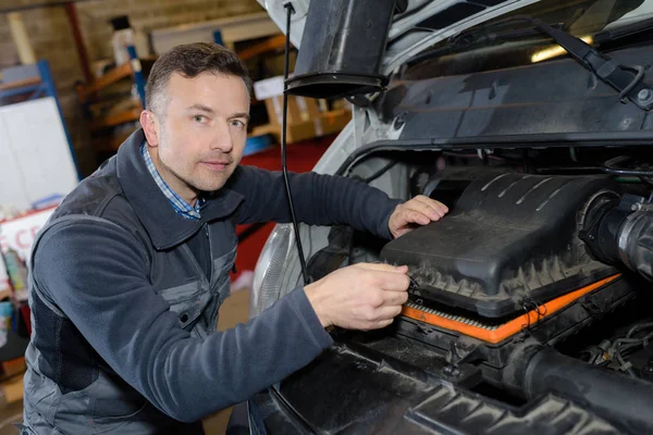 Mecánico sonriente reparación de motor de coche en un garaje — Foto de Stock