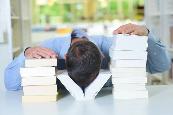 Homem com a cabeça entre duas pilhas de livros — Fotografia de Stock