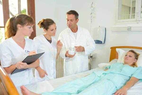 Personal médico que rodea la cama del paciente femenino — Foto de Stock