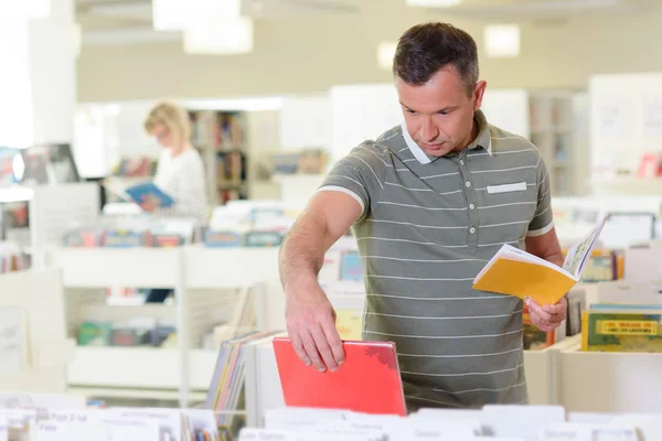 Man boek kiezen uit trolley in bibliotheek — Stockfoto