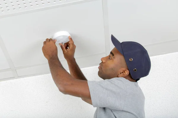 Man fitting smoke detector to ceiling — Stock Photo, Image