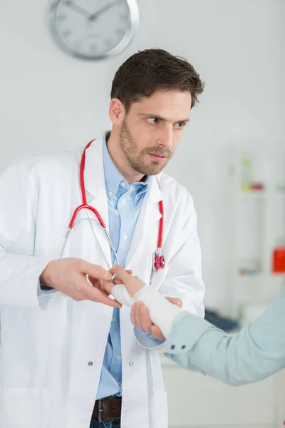 Doctor bandaging his patient hand in medical office — Stock Photo, Image