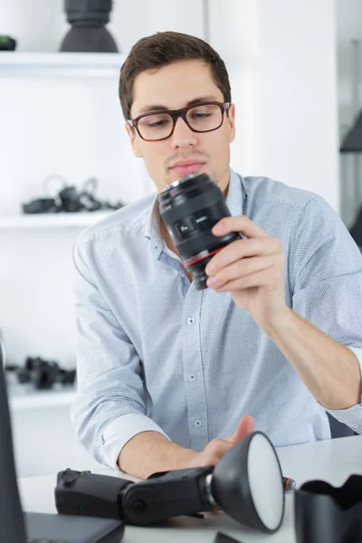 Jovem técnico confiante está consertando e limpando um cameralense digital — Fotografia de Stock