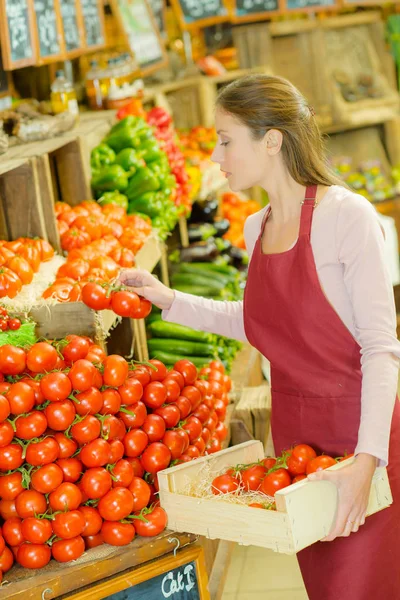 Працівник магазину з ящиком з помідорами — стокове фото