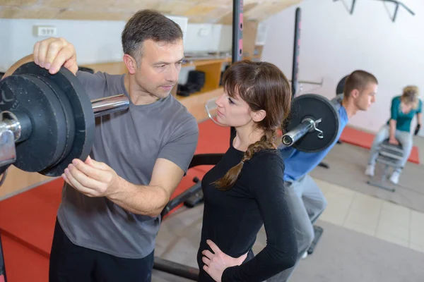 Trainer erklärt, wie man ein Trainingsgerät im Fitnessstudio einsetzt — Stockfoto