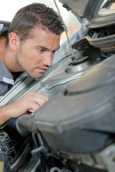 Junger Mechaniker überprüft einen Automotor — Stockfoto