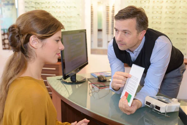 Zijaanzicht van een opticien doet zicht testen voor client — Stockfoto