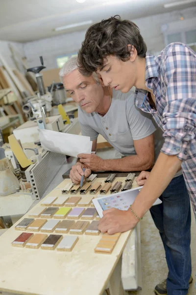 Carpenter and apprentice looking at wood samples — Stock Photo, Image