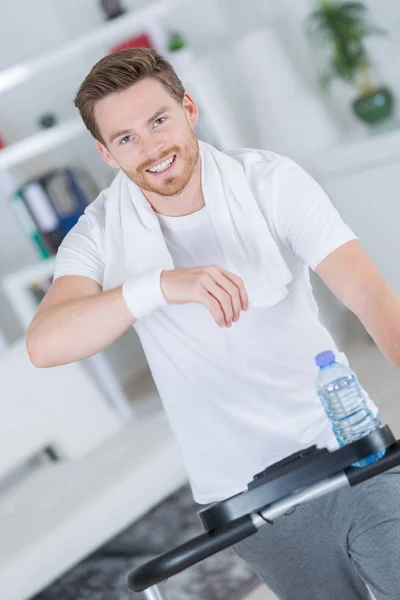 Sorrindo homem bonito formação em bicicleta de exercício — Fotografia de Stock