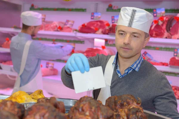 Slager brengen etiketten op gekookt vlees in slagerij — Stockfoto