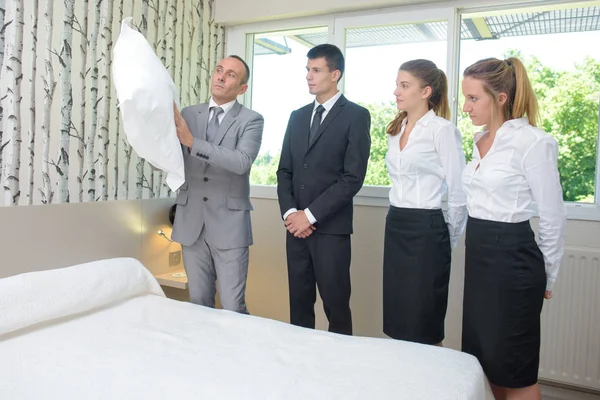 Hotel staff watching supervisor with pillow — Stock Photo, Image