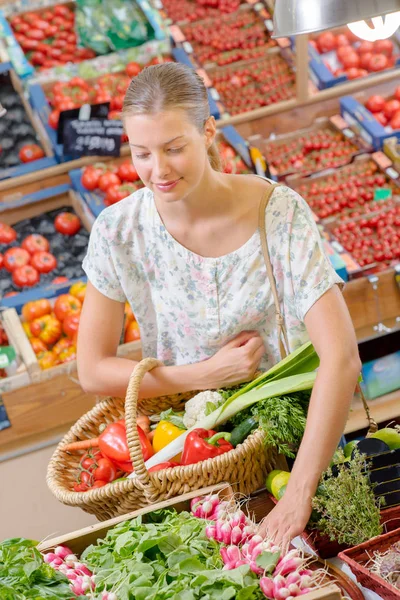 Пані тримає плетений кошик з овочів, вибираючи редьку — стокове фото