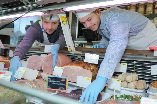 カウンターに手を伸ばす男性の肉屋 — ストック写真