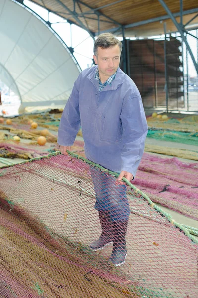 Pescador desenredando sus redes — Foto de Stock