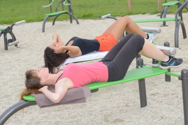 Kobiety robią siedzieć ups na park sprzętu — Zdjęcie stockowe