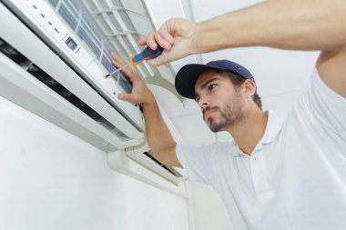 portrait of mid-adult male technician repairing air conditioner clipart