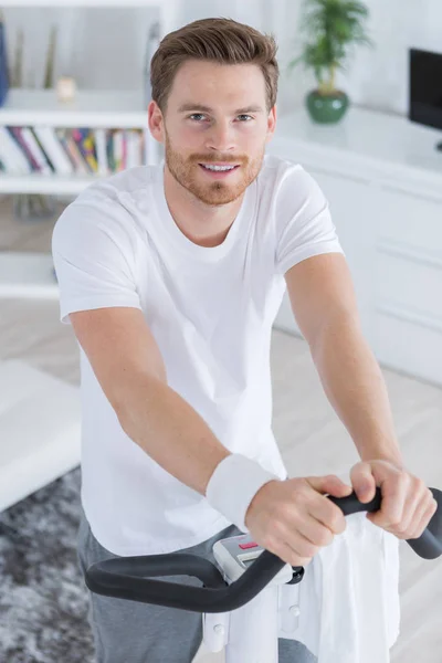Hombre usando bicicleta estática en casa — Foto de Stock