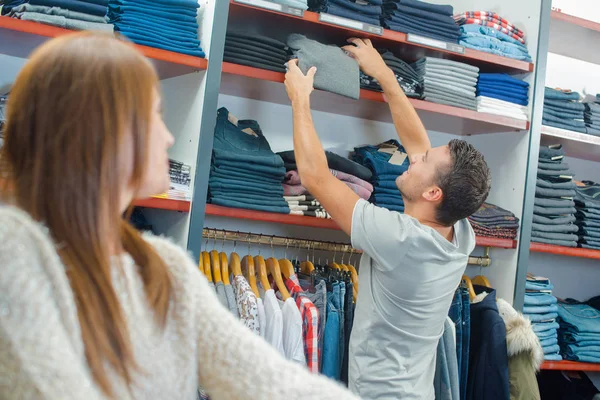 Uomo che raggiunge il maglione dallo scaffale nel negozio di vestiti — Foto Stock