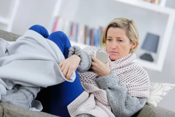 Bionda malata sdraiata sul divano con tazza — Foto Stock